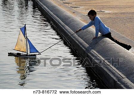 Boy playing with toy sailboat, Jardins du Luxembourg, Paris, France View Large Photo Image Stock Image - Boy playing with toy sailboat, Jardins du Luxembourg, Paris, France. Fotosearch