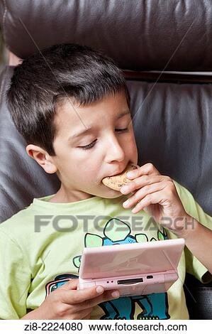 Boy plays computer games and eats biscuits. View Large Photo Image Stock Image - Boy plays computer games and eats biscuits.. Fotosearch
