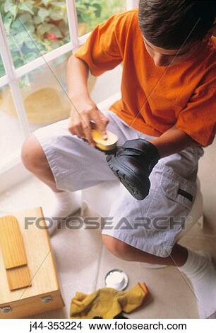 Boy polishing shoes in the house View Large Photo Image Picture - Boy polishing shoes in the house. Fotosearch