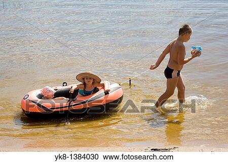 Stock Image - Boy Pulling Inflatable Boat with Kid Girls. Fotosearch