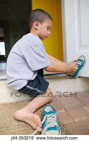 Boy putting on shoes outdoor View Large Photo Image Stock Photo - Boy putting on shoes outdoor. Fotosearch