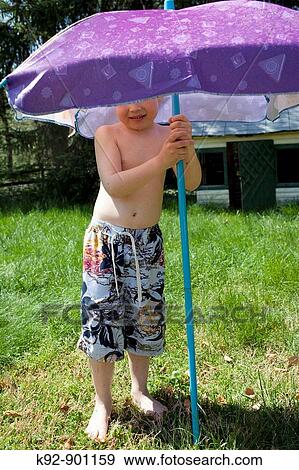 Boy putting up a sun umbrella View Large Photo Image Stock Photo - Boy putting up a sun umbrella. Fotosearch