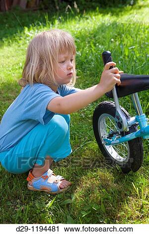 Stock Image - boy repairing bike in the garden. Fotosearch