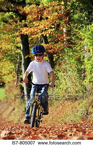 boy riding his bicycle on road with leaves in fall, autumn foliage covering path in forest, autumn, fall, Zuerich, Switzerland View Large Photo Image Stock Photo - boy riding his bicycle on road with leaves in fall, autumn foliage covering path in forest, autumn, fall, Zuerich, Switzerland. Fotosearch