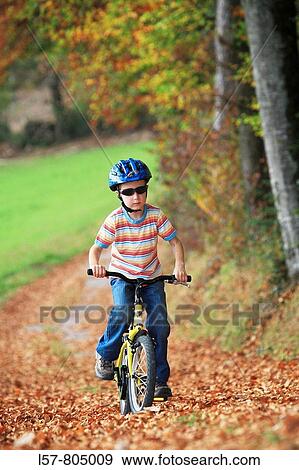 boy riding his bicycle on road with leaves in fall, autumn foliage covering path in forest, autumn, fall, Zuerich, Switzerland View Large Photo Image Stock Photo - boy riding his bicycle on road with leaves in fall, autumn foliage covering path in forest, autumn, fall, Zuerich, Switzerland. Fotosearch