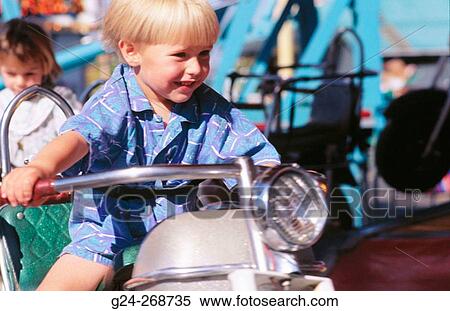 Stock Photography - Boy riding toy motorcycle at carnival. Fotosearch