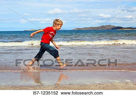Stock Image - boy running on sandy beach, Sutherland, Scotland. Fotosearch