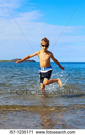 Stock Image - boy running on sandy beach, Sutherland, Scotland. Fotosearch