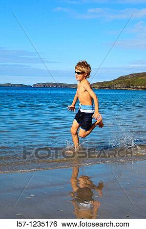 Stock Photograph - boy running on sandy beach, Sutherland, Scotland. Fotosearch