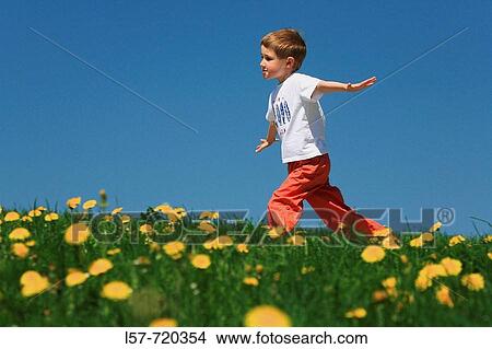 Picture - Boy running through filed of Dandelions, in spring, Switzerland.. Fotosearch