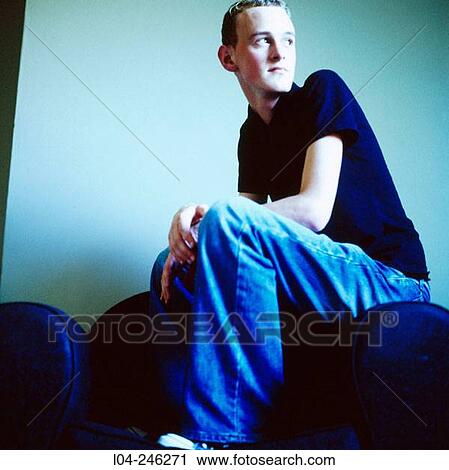 Stock Image - Boy sitting down in an armchair. Fotosearch