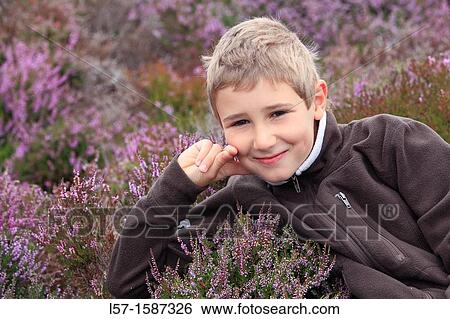 Stock Photograph - boy sitting in blooming heather field. Fotosearch