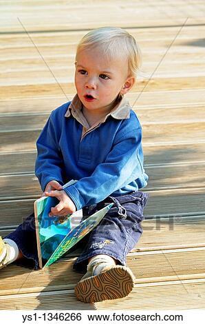 BOY SITTING, LOOKING AT BOOK View Large Photo Image Stock Photograph - BOY SITTING, LOOKING AT BOOK. Fotosearch