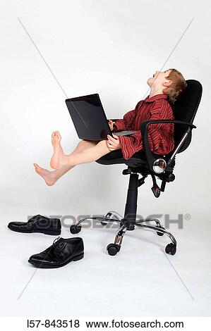 Stock Photo - boy sitting on black office chair, wearing grown up red business shirt, with laptop on his lap, frustrated, white background, Studio, Switzerland. Fotosearch