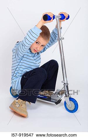 Stock Photo - boy sitting on kickboard, kick scooter, white background, Studio, Switzerland. Fotosearch