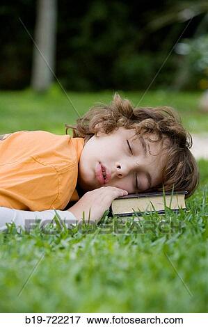 Stock Photo - Boy sleeping laying on grass. Fotosearch