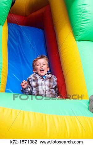 Boy sliding down an inflatable ride View Large Photo Image Stock Image - Boy sliding down an inflatable ride. Fotosearch