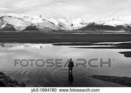 Stock Image - Boy standing in a Lake, near Hofn, Iceland. Fotosearch