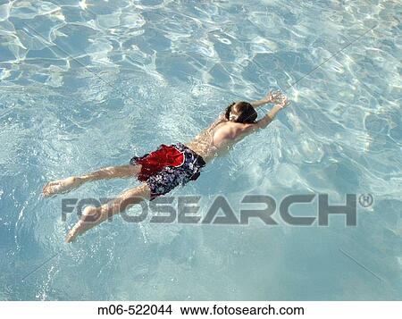 Picture - Boy swimming underwater in a swimming pool.. Fotosearch