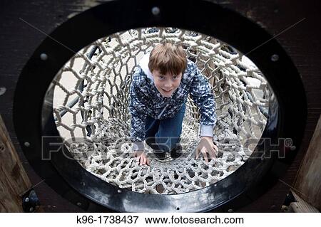 boy triumphantly climbing rope tunnel View Large Photo Image Stock Photo - boy triumphantly climbing rope tunnel. Fotosearch