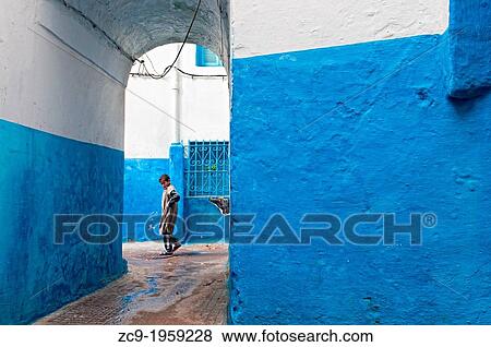 Boy walking by the blue streets of Larache medina, Morocco. View Large Photo Image Stock Photo - Boy walking by the blue streets of Larache medina, Morocco.. Fotosearch