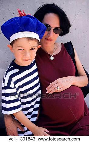 Boy wearing a hat and standing next to his pregnant mother View Large Photo Image Stock Image - Boy wearing a hat and standing next to his pregnant mother. Fotosearch