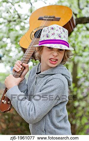 Boy with an acoustic guitar playing outdoor in the garden. View Large Photo Image Stock Photo - Boy with an acoustic guitar playing outdoor in the garden.. Fotosearch