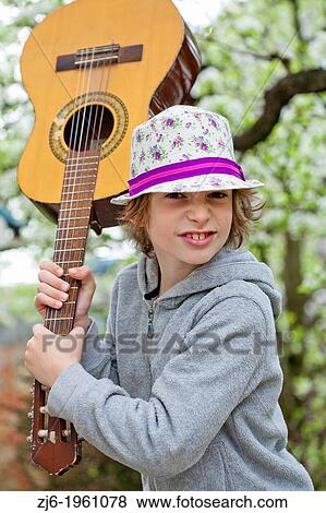 Stock Photo - Boy with an acoustic guitar playing outdoor in the garden.. Fotosearch