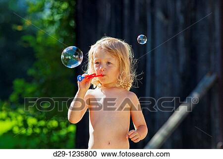 boy with long blond hair blowing soap bubbles View Large Photo Image Stock Image - boy with long blond hair blowing soap bubbles. Fotosearch