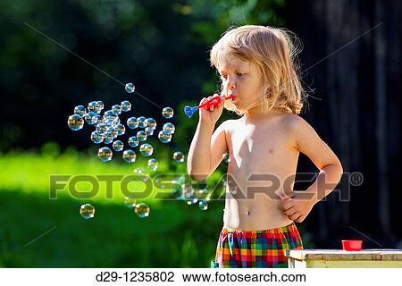 boy with long blond hair blowing soap bubbles View Large Photo Image Stock Image - boy with long blond hair blowing soap bubbles. Fotosearch