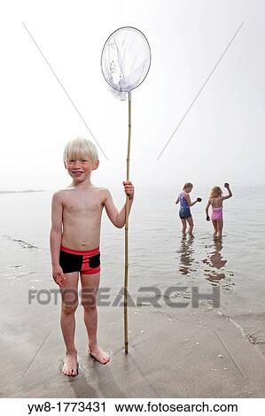 Stock Image - Boy with net at the beach, girls in the water, Akranes, Iceland. Fotosearch