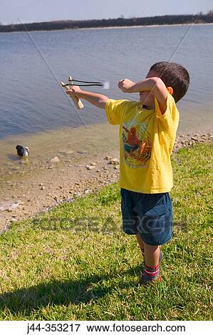 Boy with slingshot by the lake View Large Photo Image Stock Photo - Boy with slingshot by the lake. Fotosearch