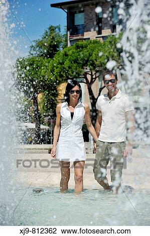 Stock Image - Boyfriends walking inside fountain.. Fotosearch