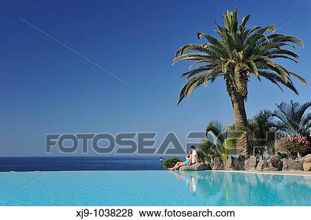 Stock Photo - Boys and girls sat facing the sea and pool. Fotosearch