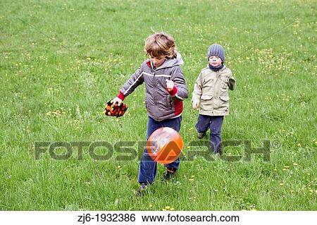 Stock Photograph - Boys chasing ball. Slovenia Europe.. Fotosearch