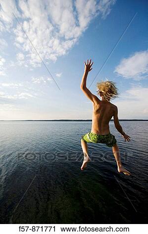 Stock Image - Boys leaping off a pier in Denmark. Fotosearch