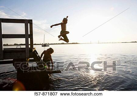 Boys leaping off a pier in Denmark View Large Photo Image Stock Photo - Boys leaping off a pier in Denmark. Fotosearch
