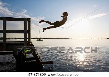 Boys leaping off a pier in Denmark View Large Photo Image Stock Photo - Boys leaping off a pier in Denmark. Fotosearch