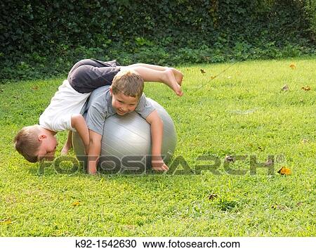 Boys playing on an exercise ball. View Large Photo Image Stock Image - Boys playing on an exercise ball.. Fotosearch