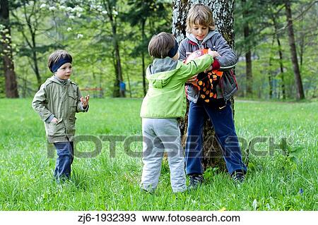 Stock Image - Boys playing outdoor with ball. Older boy took the ball to the younger one causing conflict.. Fotosearch