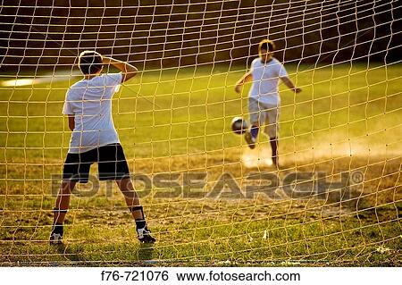 Boys playing soccer at net View Large Photo Image Stock Photograph - Boys playing soccer at net. Fotosearch