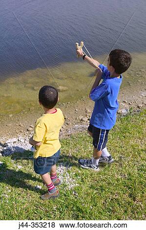 Boys with slingshot by the lake View Large Photo Image Stock Photo - Boys with slingshot by the lake. Fotosearch
