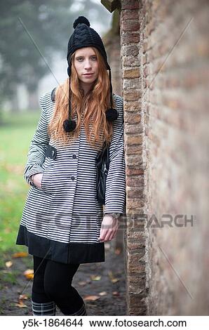 Breda, Netherlands. Young, fashionable and redheaded woman in a city-park, leaning against a wall. View Large Photo Image Picture - Breda, Netherlands. Young, fashionable and redheaded woman in a city-park, leaning against a wall.. Fotosearch