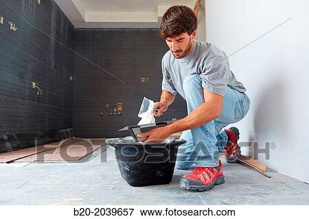 Stock Photo - Bricklayer applying tile adhesive for tiling. Construction of residential building. Donostia. San Sebastian. Gipuzkoa. Basque Country. Spain.. Fotosearch