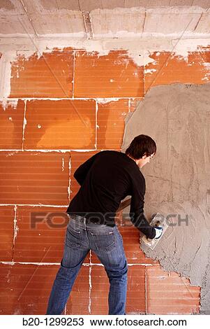 Stock Image - Bricklayer, rendering a partition wall, new homes under construction, construction site. Fotosearch