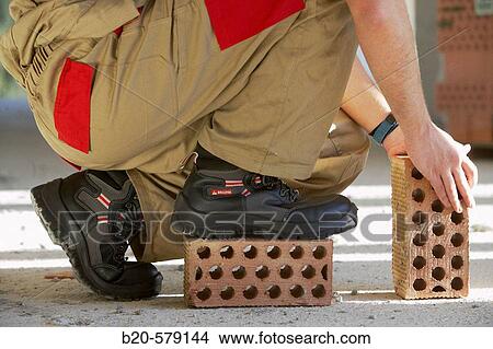Bricklayer with safety boots, bricks, housing construction View Large Photo Image Picture - Bricklayer with safety boots, bricks, housing construction. Fotosearch