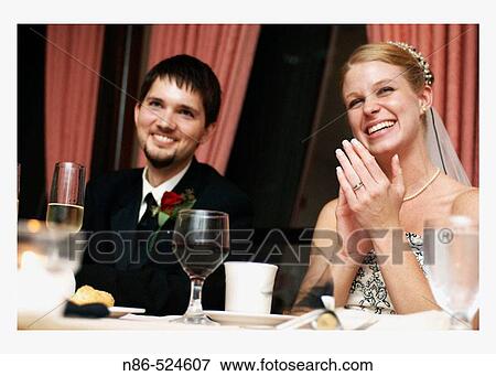 Stock Photo - Bride and groom at dinner table clapping. Fotosearch