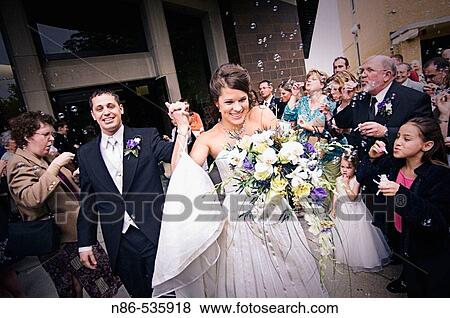 Bride and groom departing church and crowd with bubbles View Large Photo Image Stock Photo - Bride and groom departing church and crowd with bubbles. Fotosearch