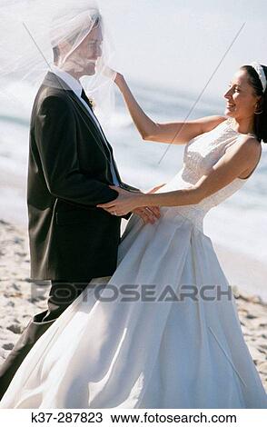 Bride and groom having fun on beach with wedding veil View Large Photo Image Stock Image - Bride and groom having fun on beach with wedding veil. Fotosearch
