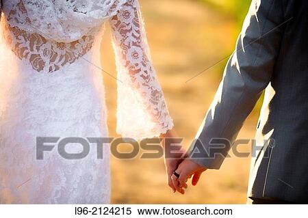 bride and groom holding hands walking into the reception party View Large Photo Image Stock Photography - bride and groom holding hands walking into the reception party. Fotosearch
